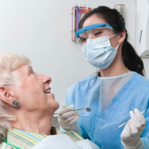 Masked dentist with older woman