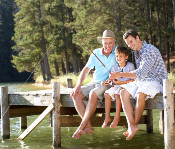 Father, son and grandson fishing together sitting on pier
